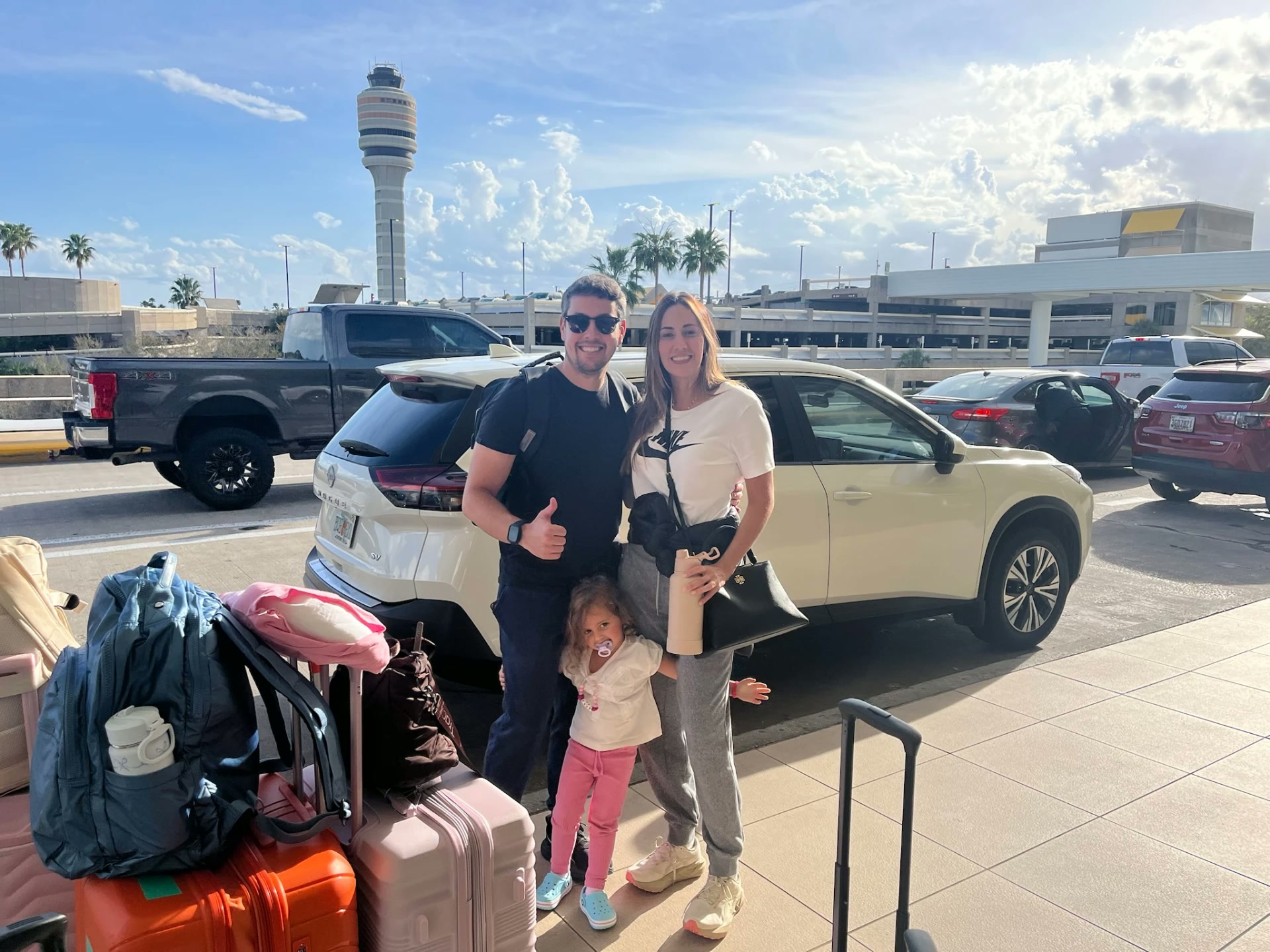 Família brasileira com as malas ao lado do carro alugado com a MOVE, no aeroporto da Flórida